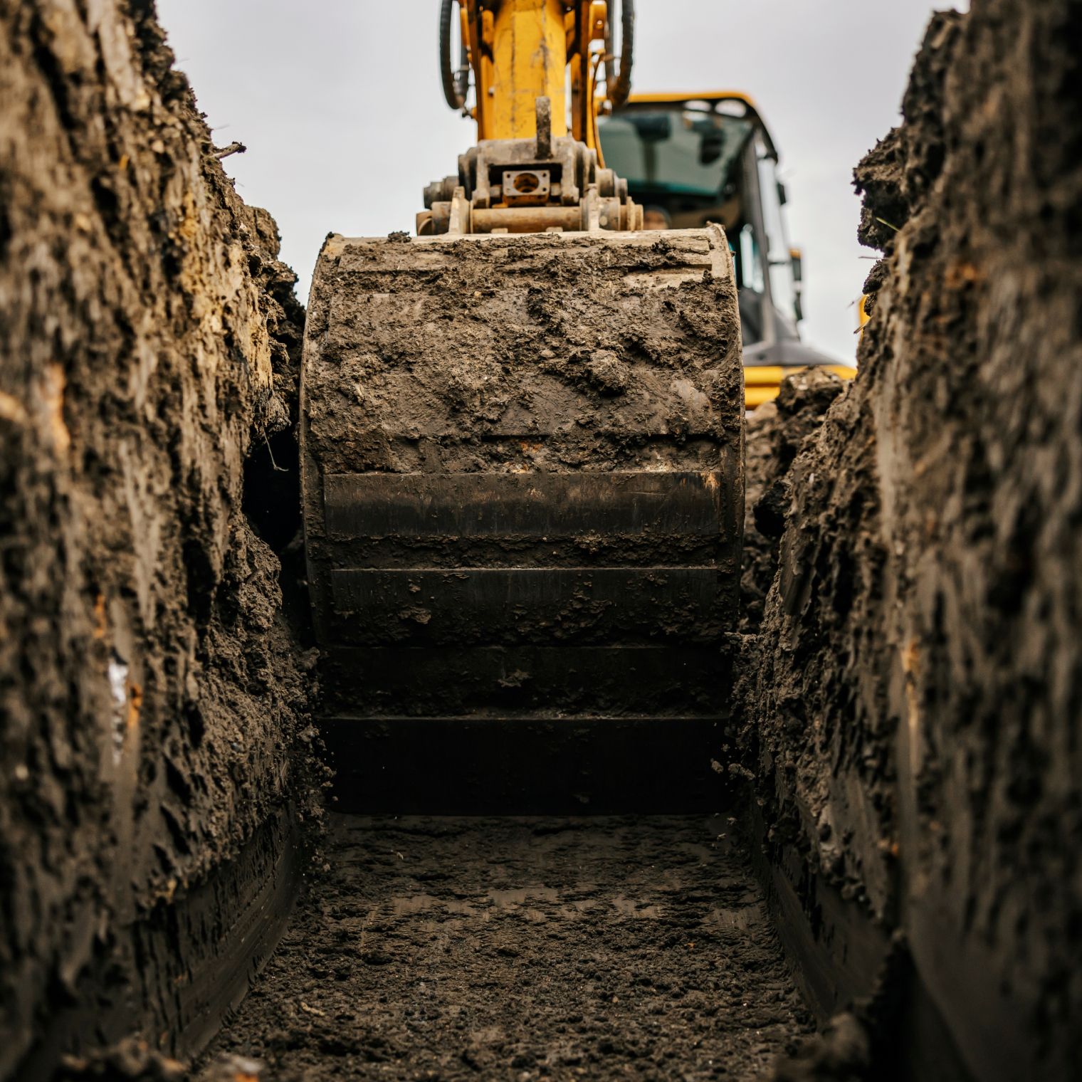Gelber Bagger beim ausheben eines Grabens